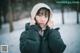 A woman wearing a black jacket and a white hat in the snow.