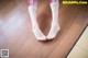 A woman's feet with red nail polish on a wooden floor.