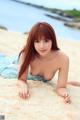 A woman laying on a sandy beach next to the ocean.