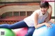 A young woman sitting on top of a blue and green ball.