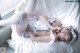 A woman laying on top of a bed in a white dress.